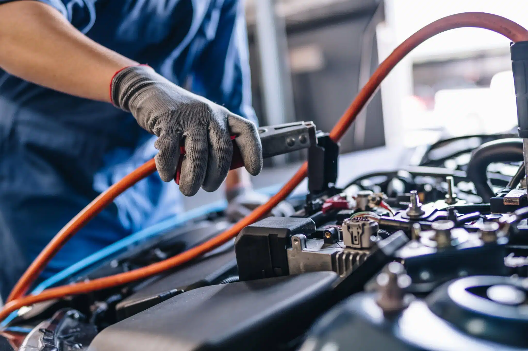 Mechanic using jumper cables to start car battery in Singapore workshop