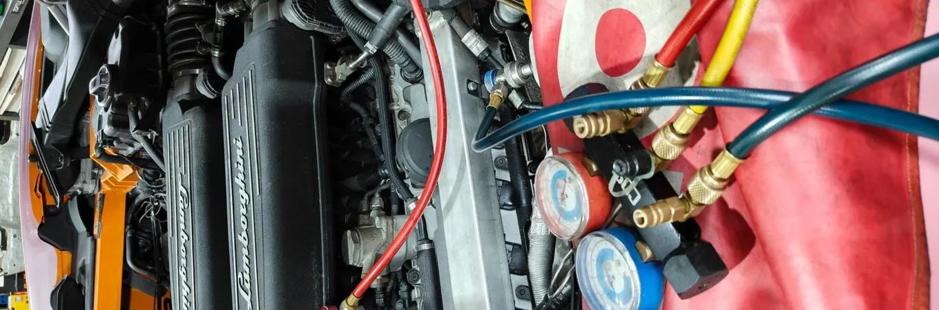 Close-up of Lamborghini engine undergoing diagnostics with pressure gauges and hoses connected