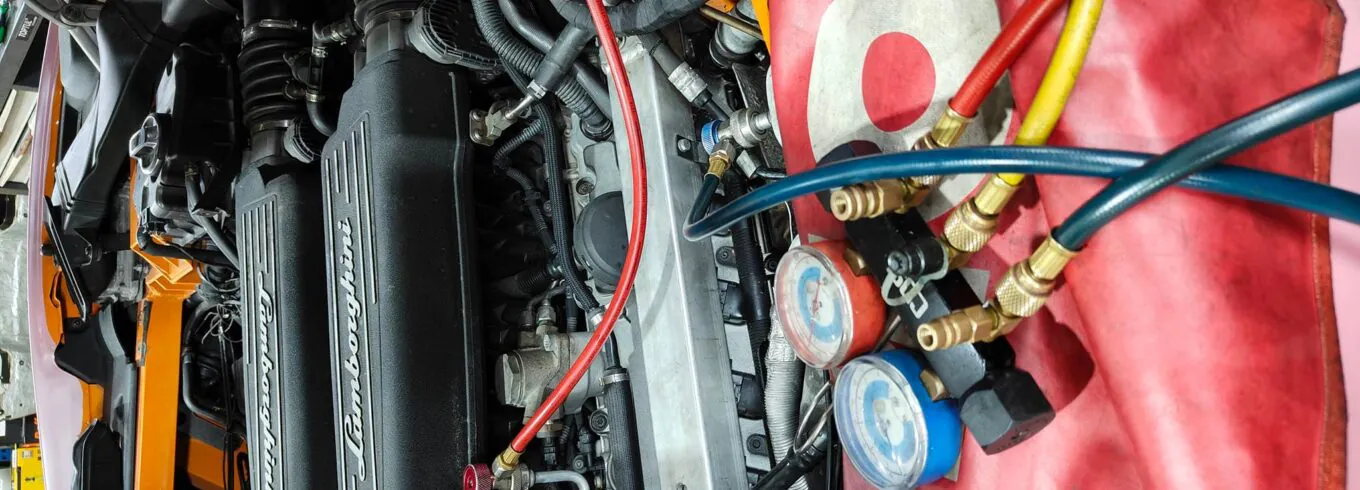 Close-up of Lamborghini engine undergoing diagnostics with pressure gauges and hoses connected